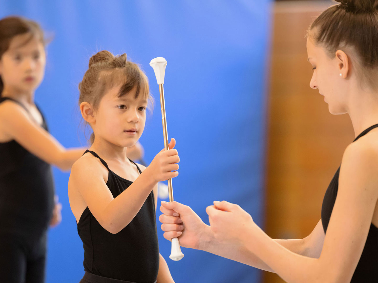 Twirlingtrainerin zeigt junger Sportlerin neue Übung mit dem Baton